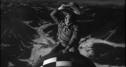 A screencap from "Dr. Strangelove" showing a man in cowboy hat riding an atomic bomb like a cowboy as it's deployed